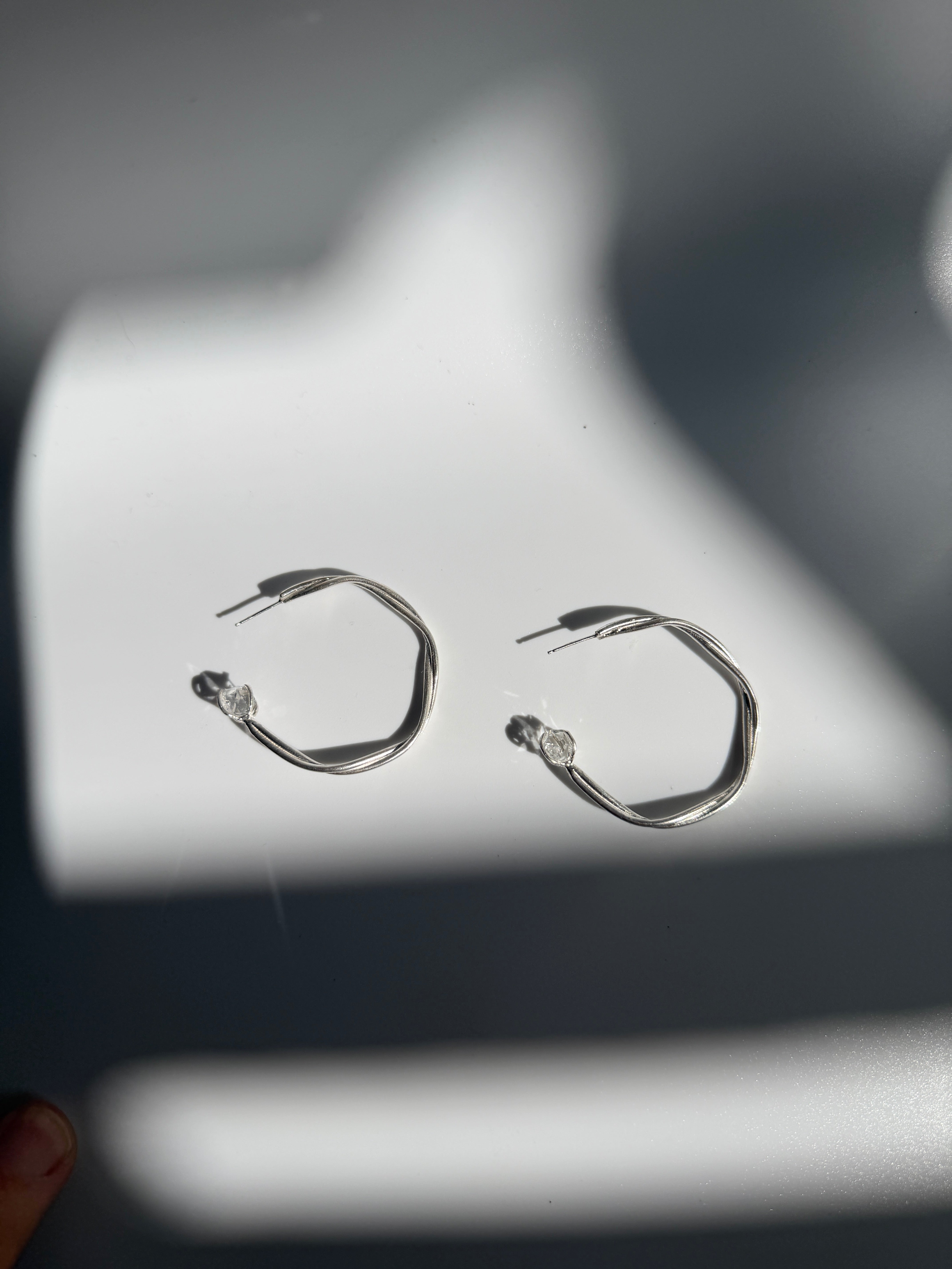 Astraea Twist Hoop Earrings in sterling silver featuring Herkimer diamond gemstones, handcrafted with elegant twisted detailing and inspired by celestial beauty.