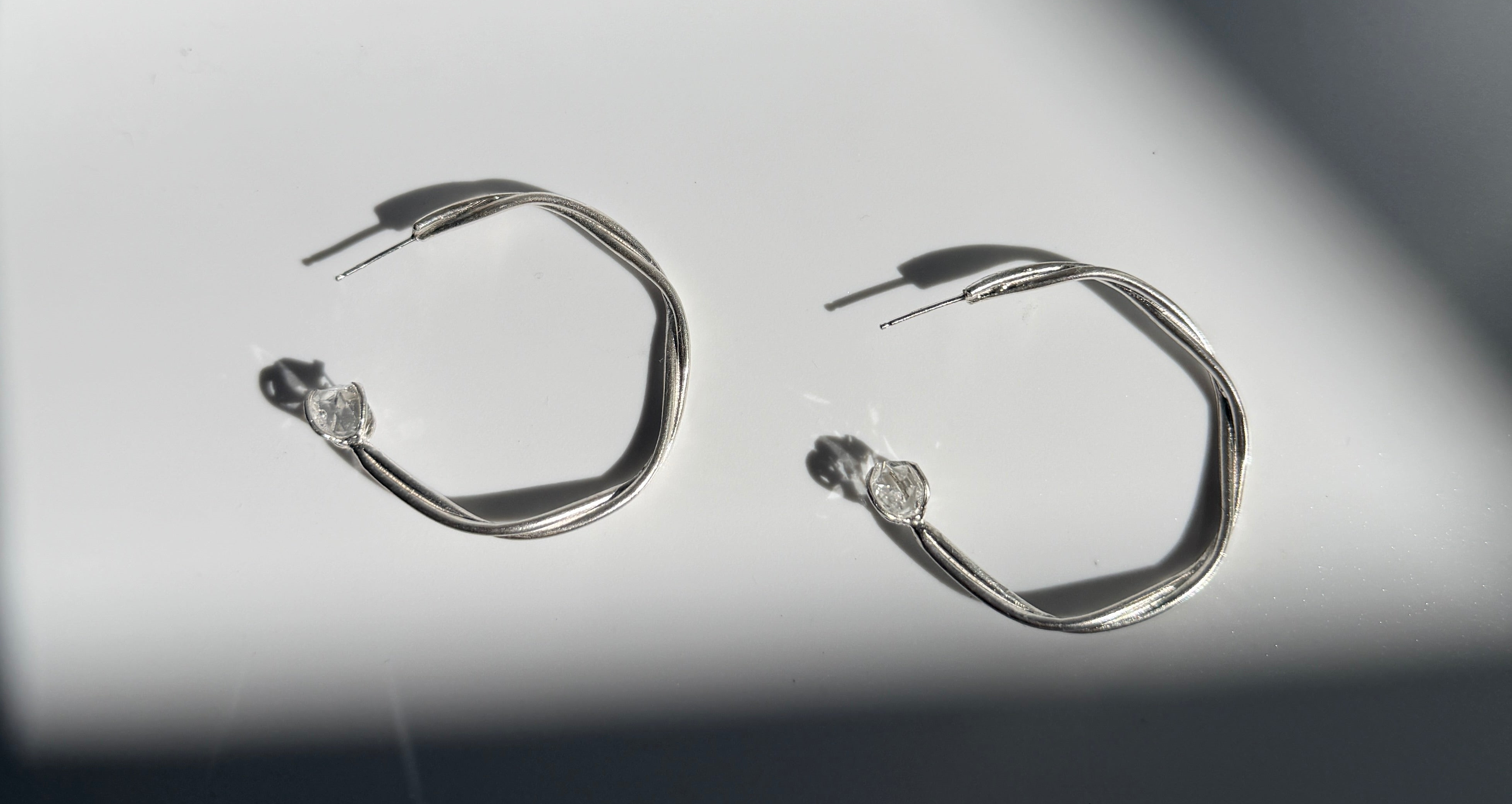 Astraea Twist Hoop Earrings in sterling silver featuring Herkimer diamond gemstones, handcrafted with elegant twisted detailing and inspired by celestial beauty.