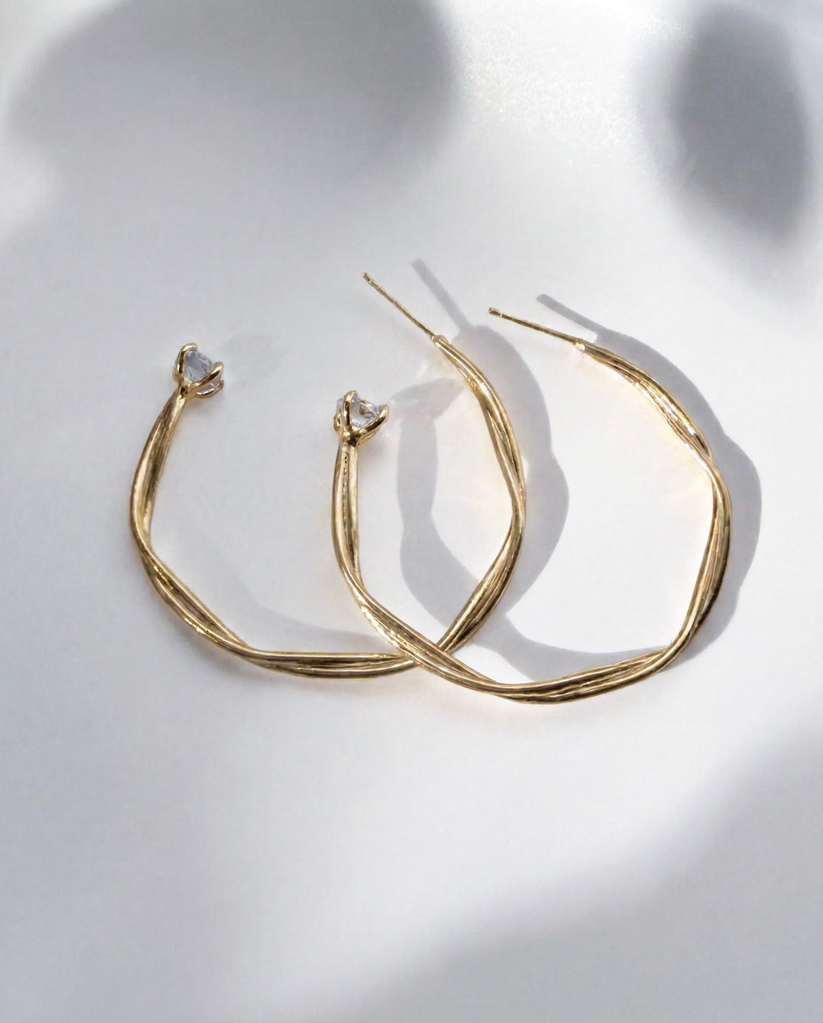 Astraea Twist Hoop Earrings in gold vermeil with a Herkimer diamond quartz crystal at the base, handcrafted in New York City by Kefi