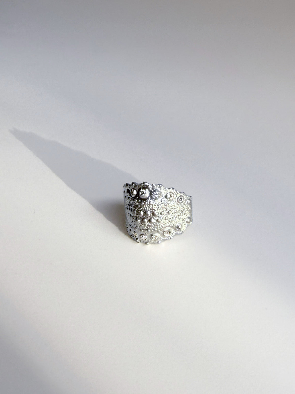 Galatea Urchin Ear Cuff in sterling silver with flush-set diamonds, cast from a sea urchin shell, shown in soft side light