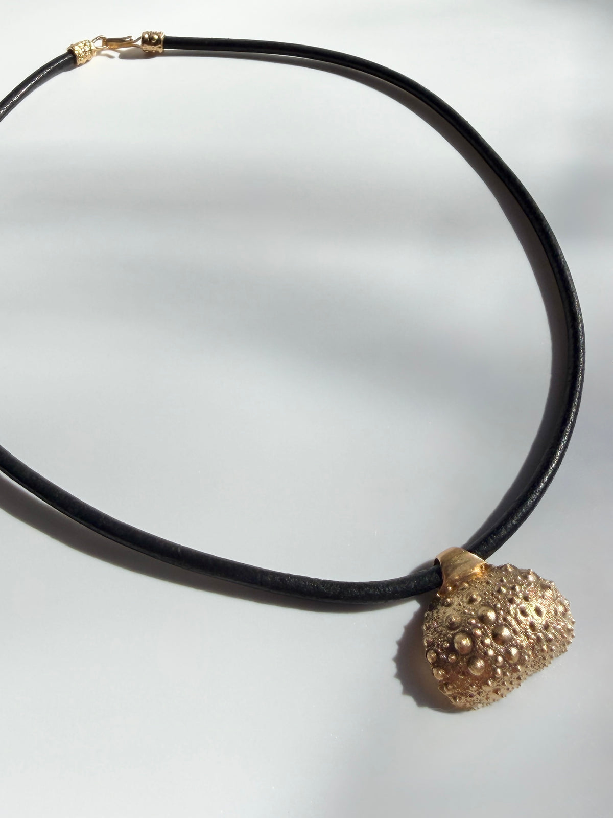 Thalassa Urchin Necklace in gold vermeil, a sea urchin pendant on a black leather cord