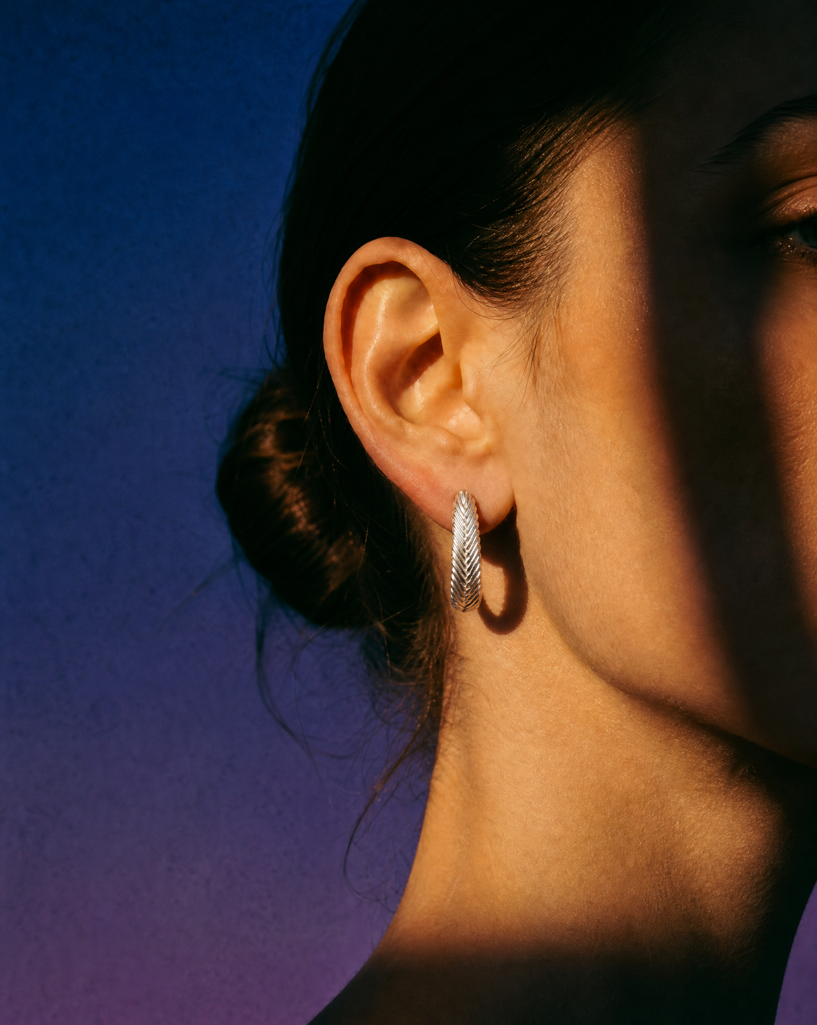 Model wearing sterling silver Harmonia Woven Hoop Earrings with textured handwoven detailing by Kefi.