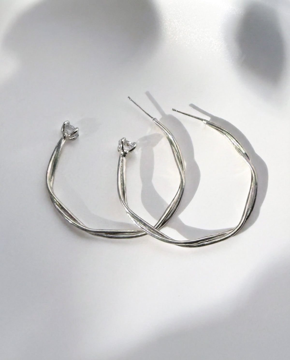 Astraea Twist Hoop Earrings in sterling silver with a Herkimer diamond quartz crystal from Upstate New York at the base