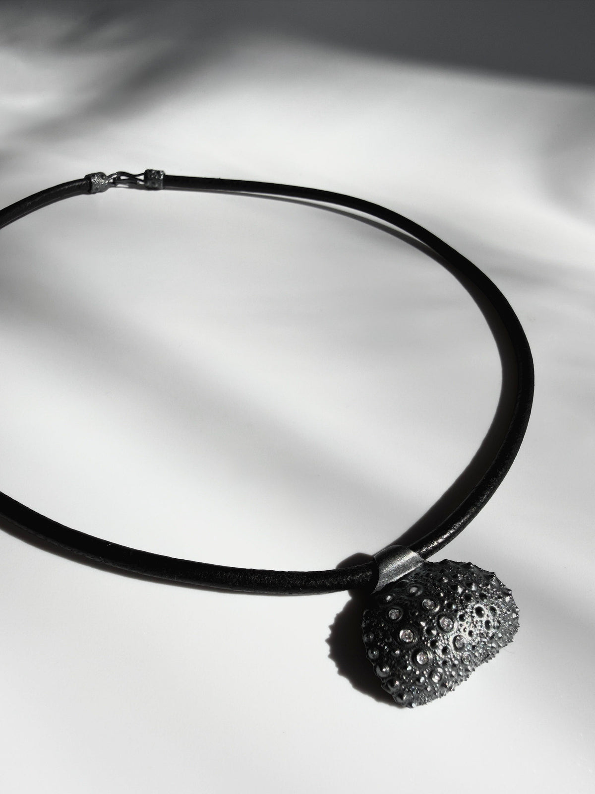 Thalassa Urchin Necklace in oxidized sterling silver, a sea urchin pendant on a black leather cord